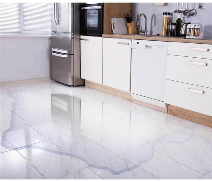 A kitchen that has standing water on the floor. 